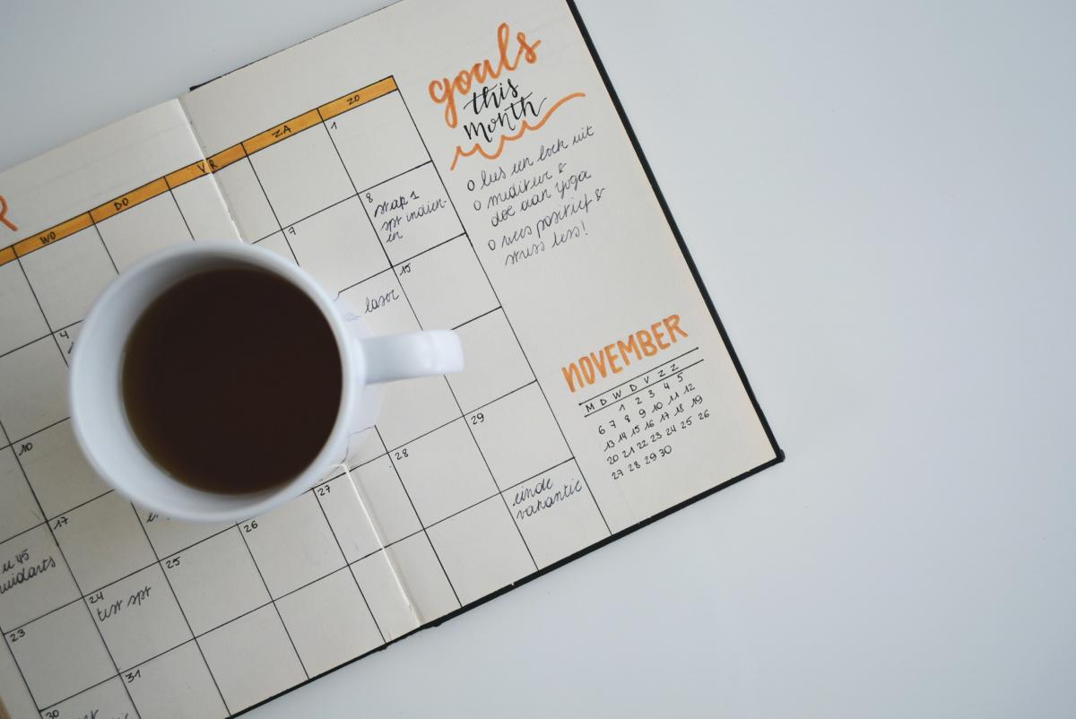 Coffee mug on top of open planner on a table.
