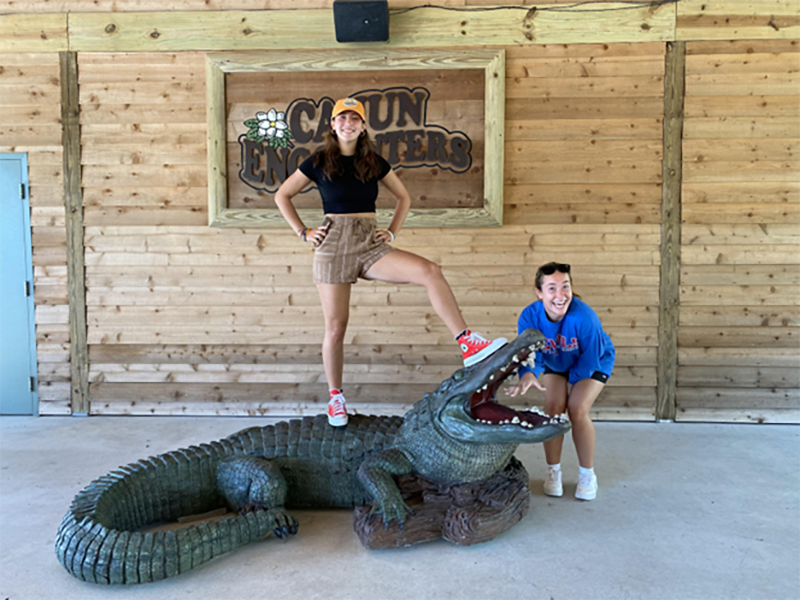 Two students posing with an alligator sculpture