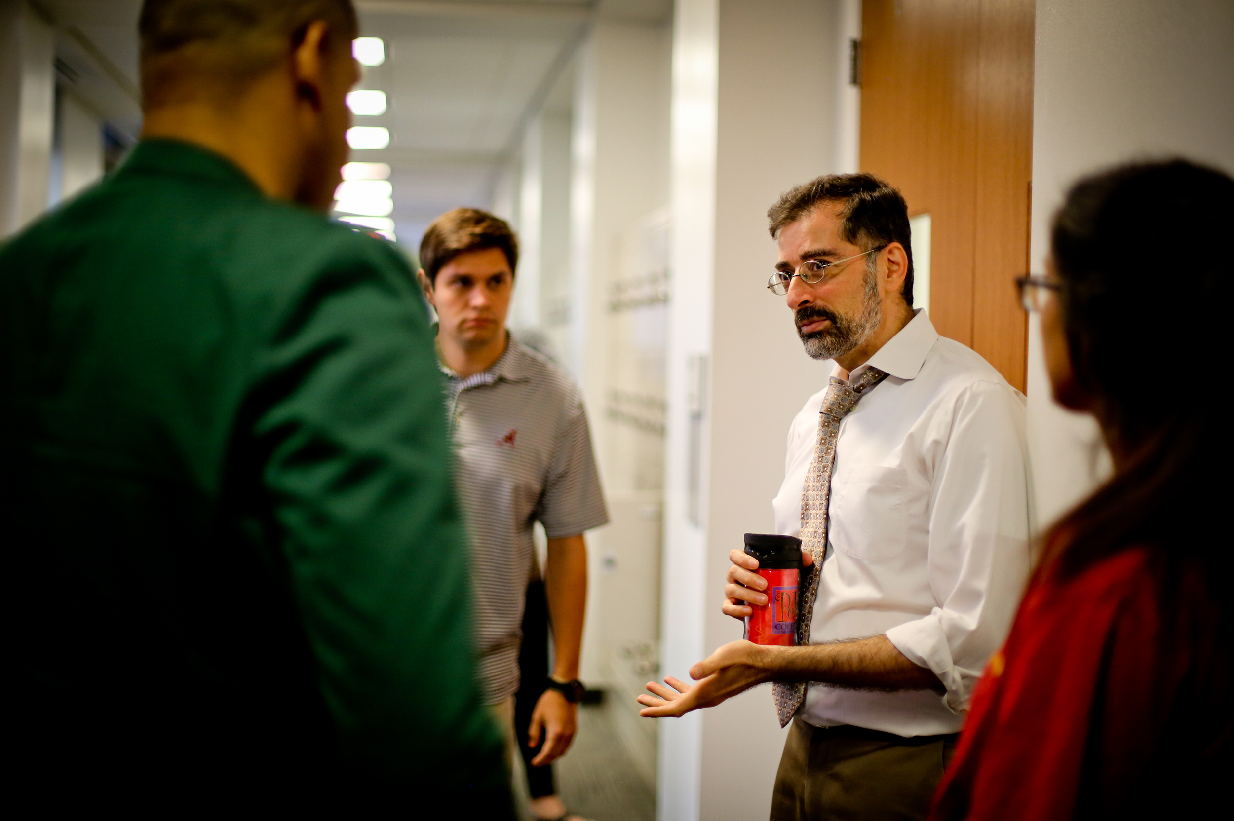 Professor talking to students in a hallway. 