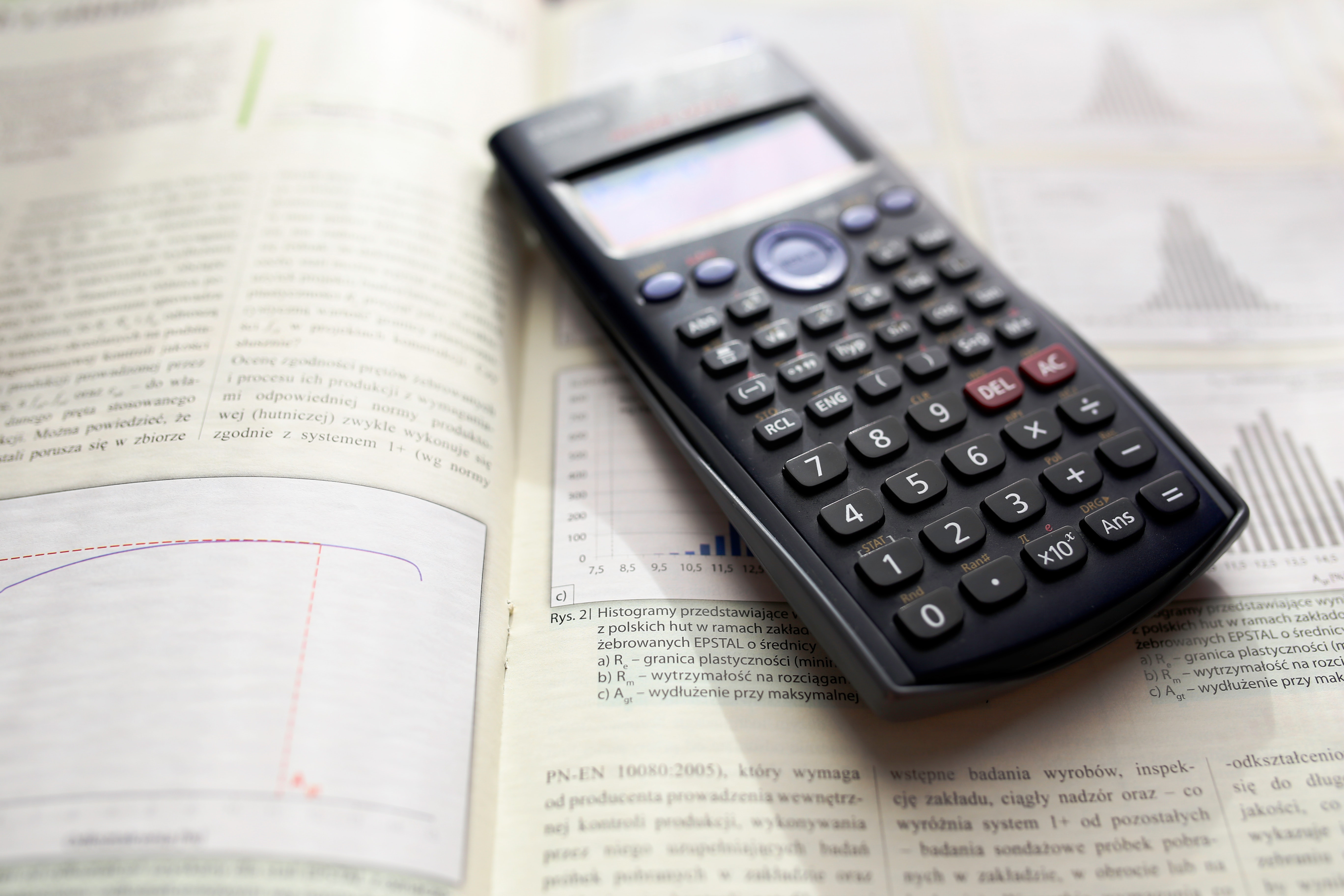 Calculator resting on an math open textbook.