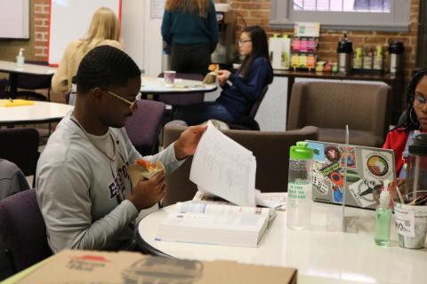 Student studying while eating pizza.