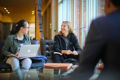 Group of four students sitting by the windows at the Tulane business school.