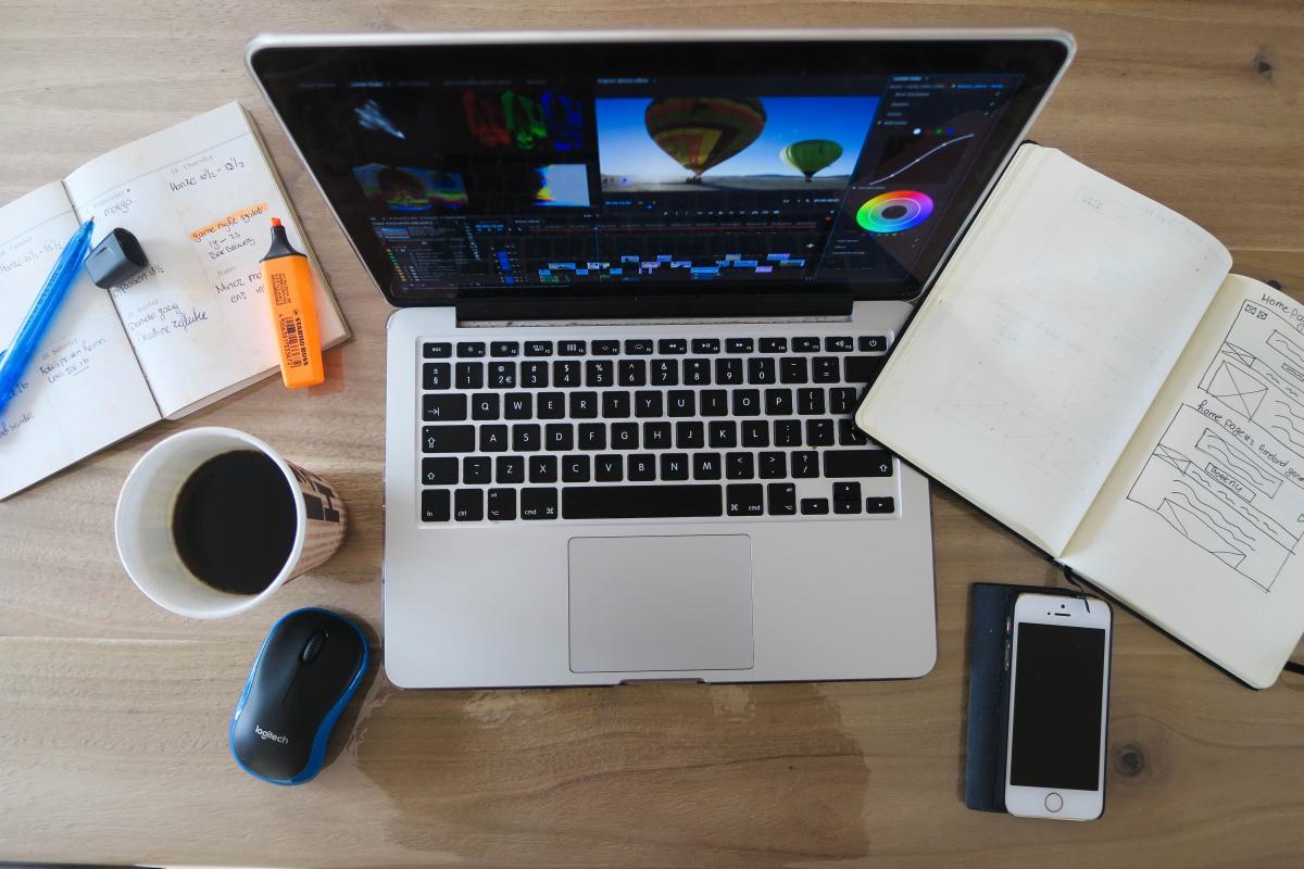 Desk with open laptop, notebooks, and highlighters on it. 