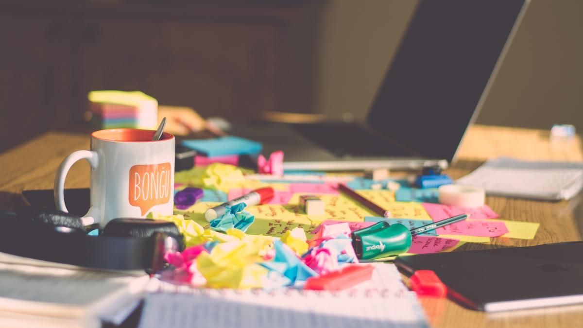 Desk covered in crumpled paper next to a laptop.